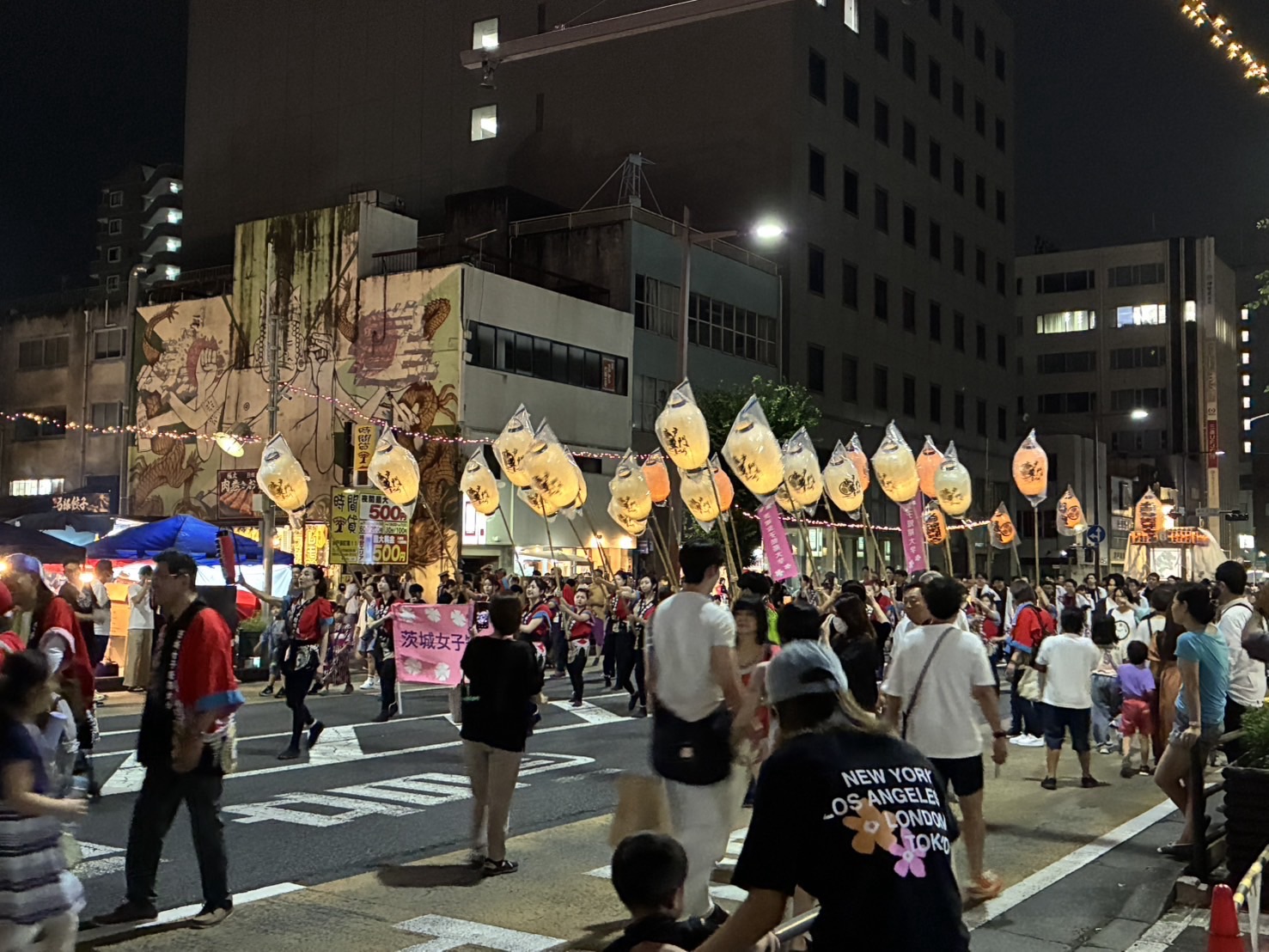 水戸市の水戸黄門まつりで、夜の通りを練り歩く提灯を持った参加者と、沿道に集まる人々のにぎやかな様子
